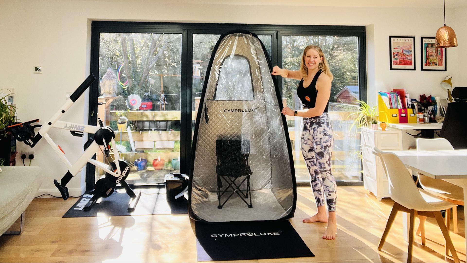 a woman stands next to a pop-up sauna pod in her home