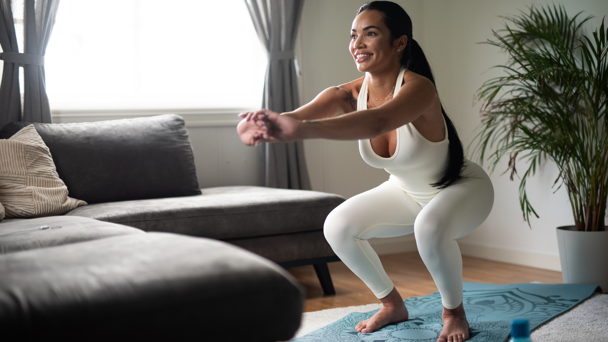 Woman performing a squat next to a couch