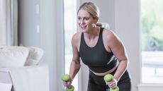 Woman exercising with dumbbells in domestic setting