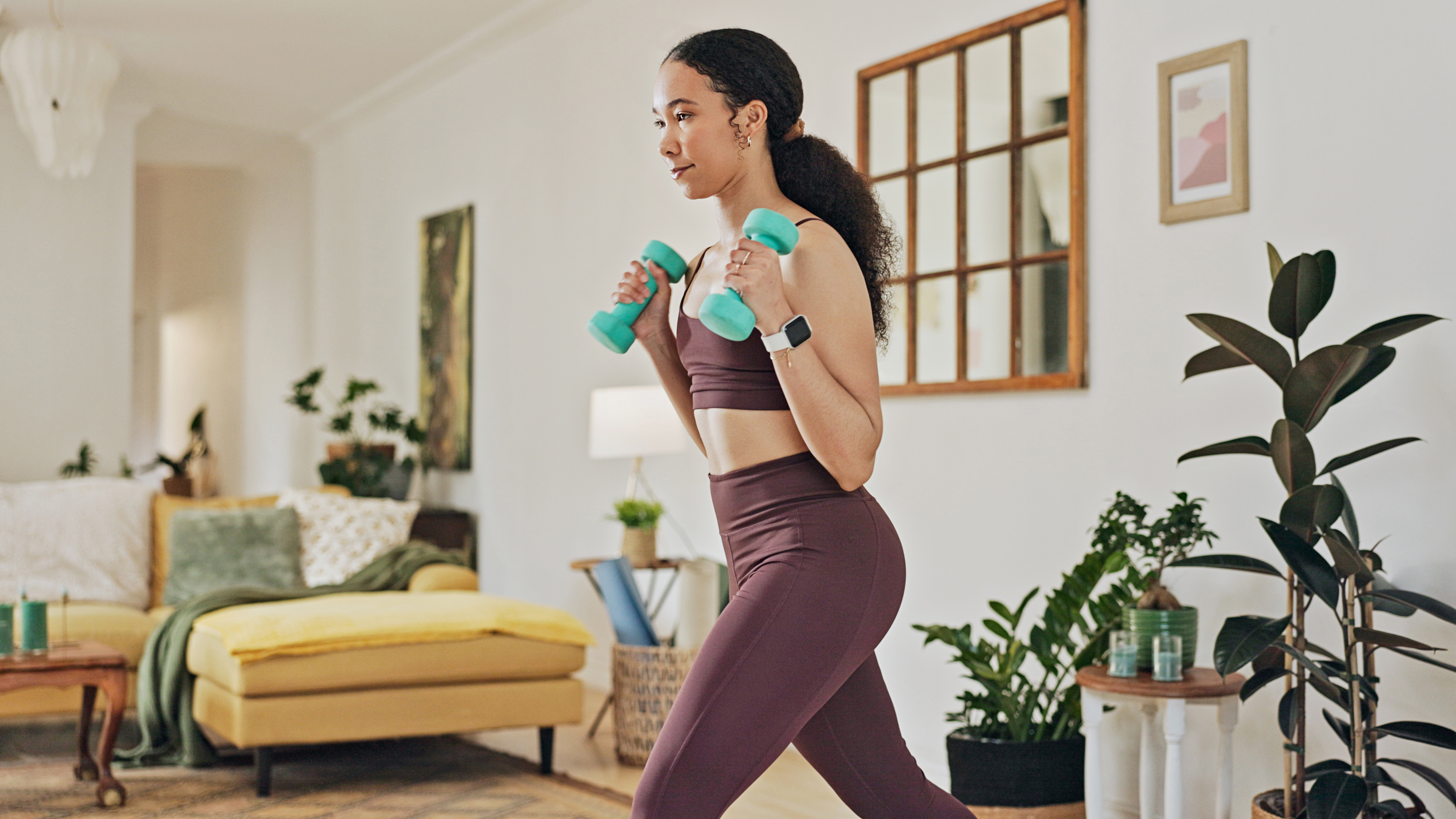 Woman exercising with dumbbells in domestic setting
