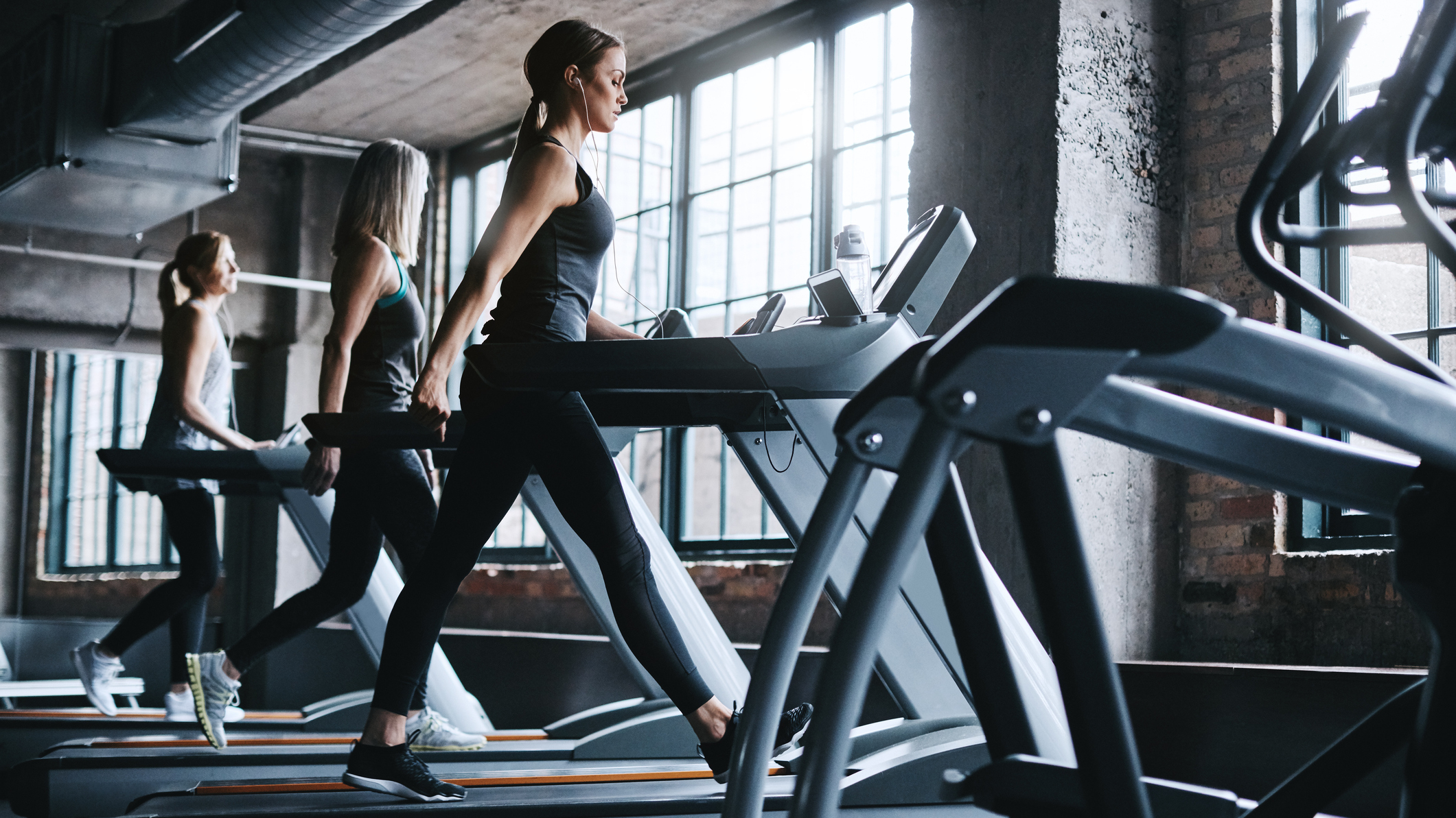 Three women walking on treadmills in a gym