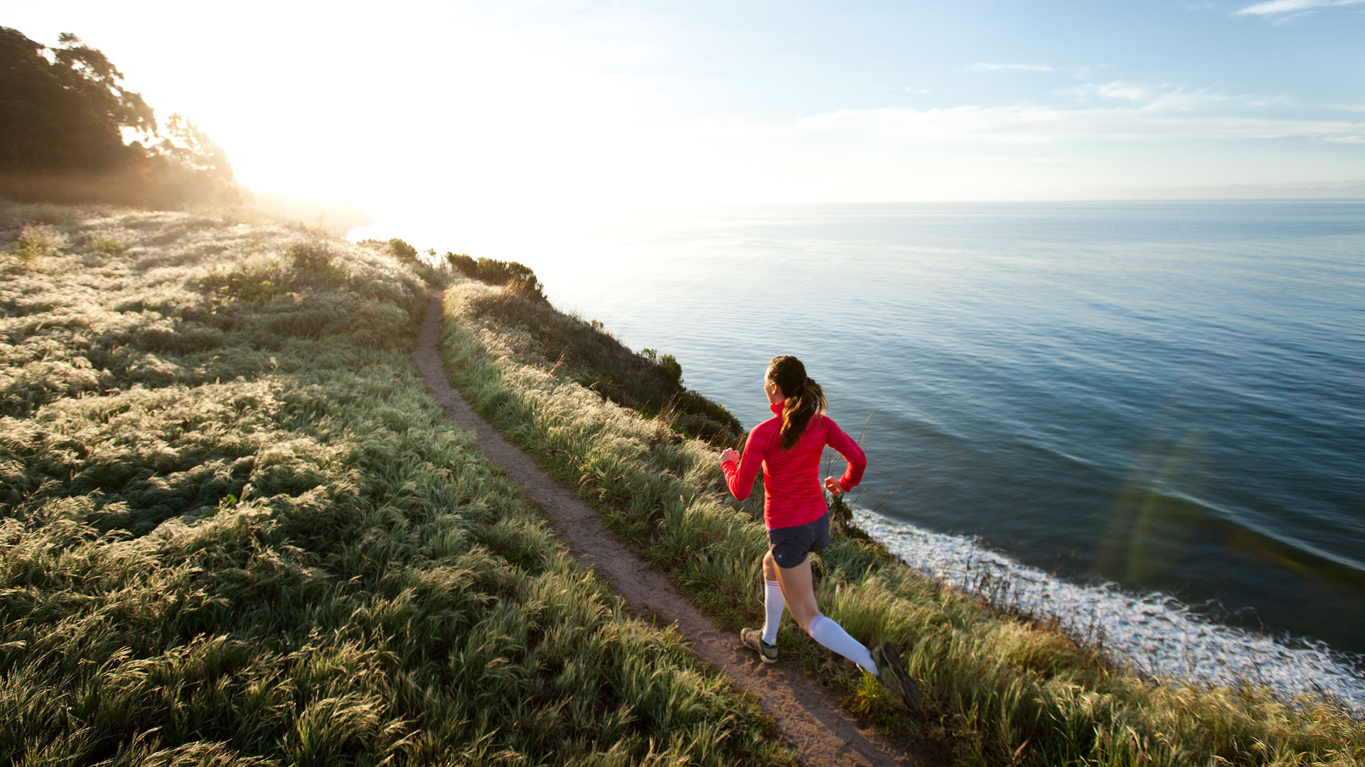 Woman running on a coastal path overlooking the sea