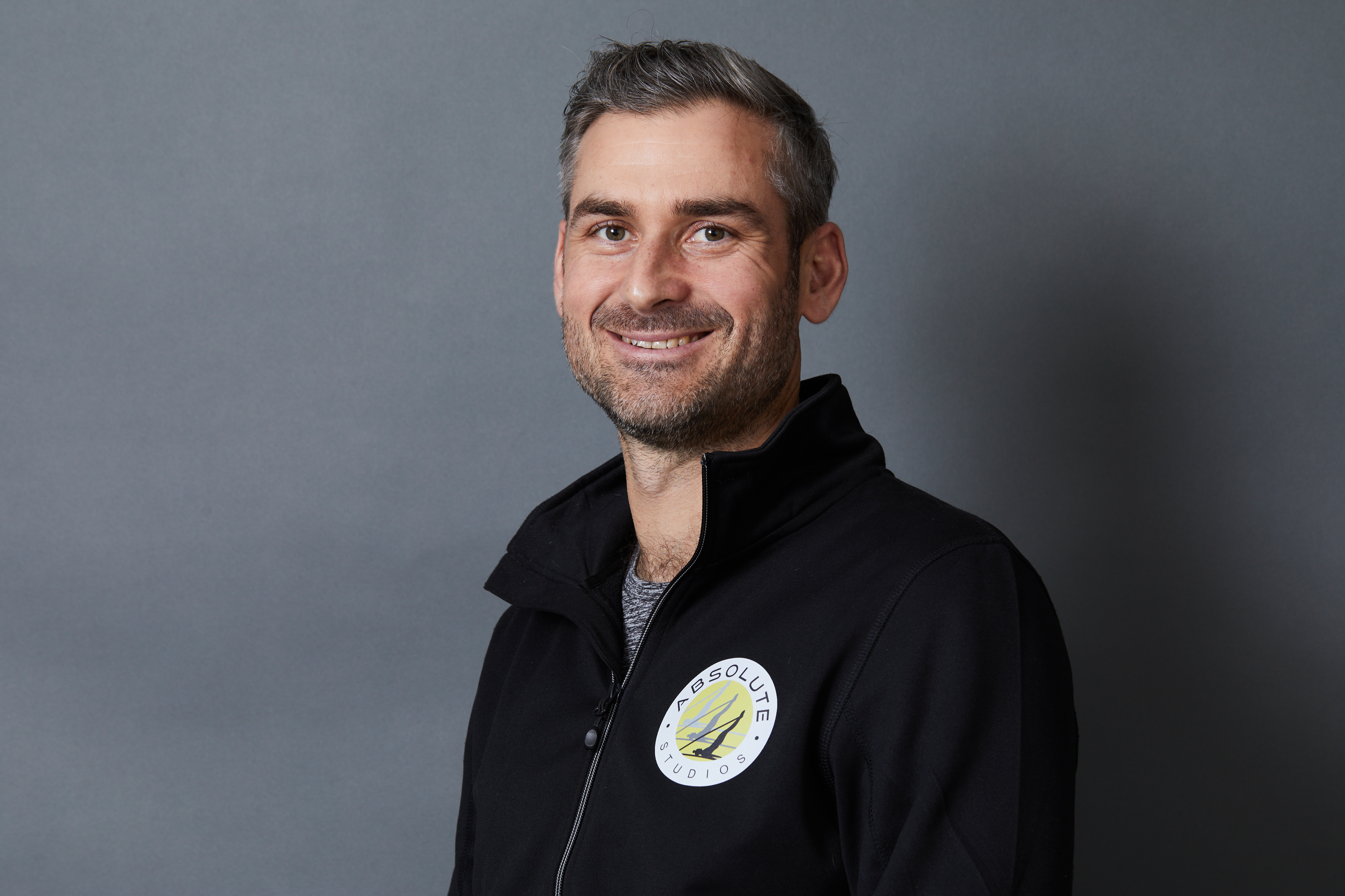 Man wearing zip-up fleece smiles at camera