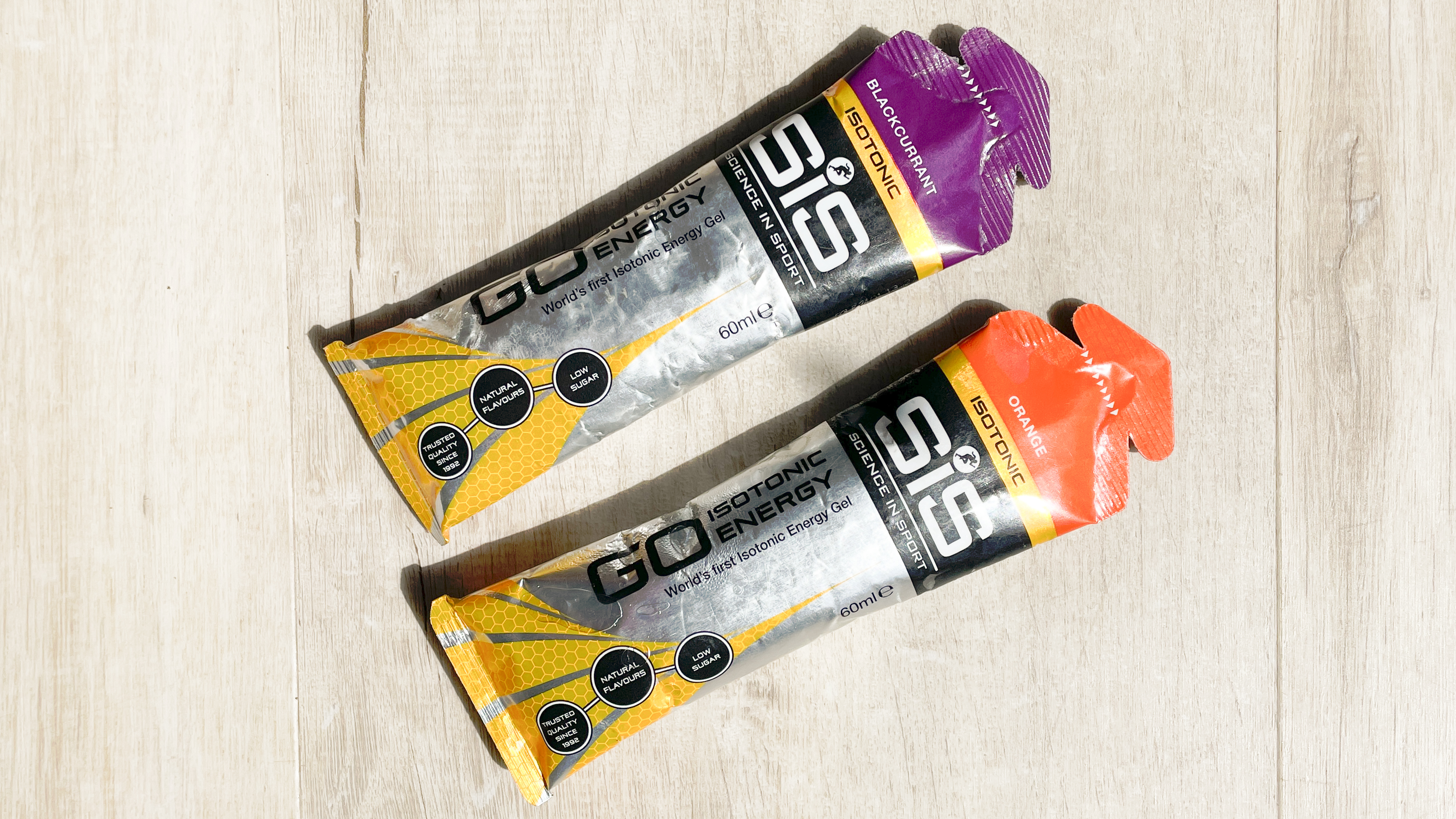 Two SIS Isotonic running gels on a wooden floor