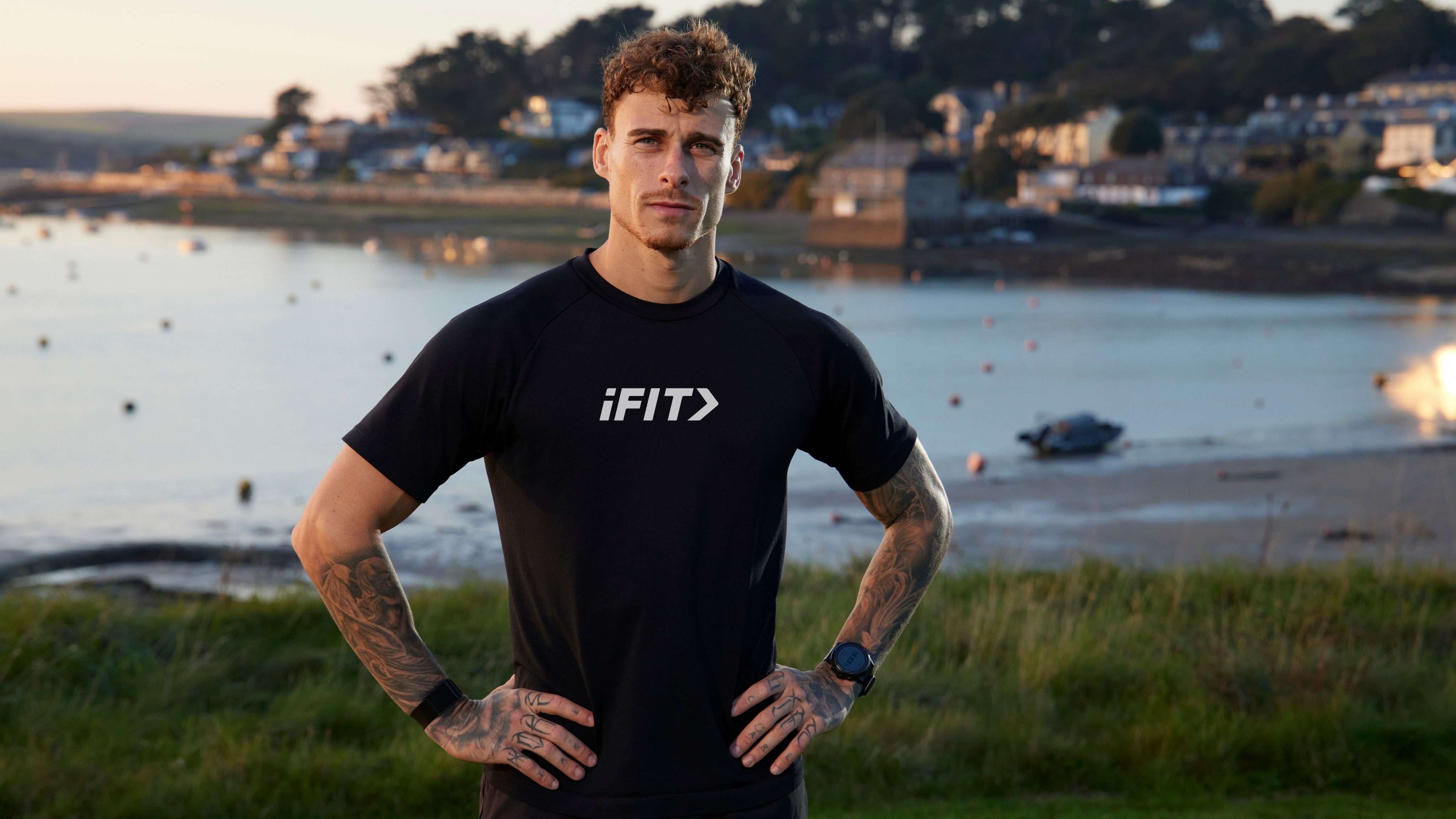 Man wearing a black T-shirt with iFit written on it, with bay behind him